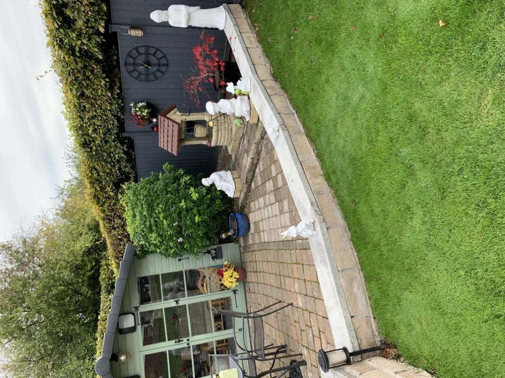 Lawn and paved seating area beside a garden summerhouse