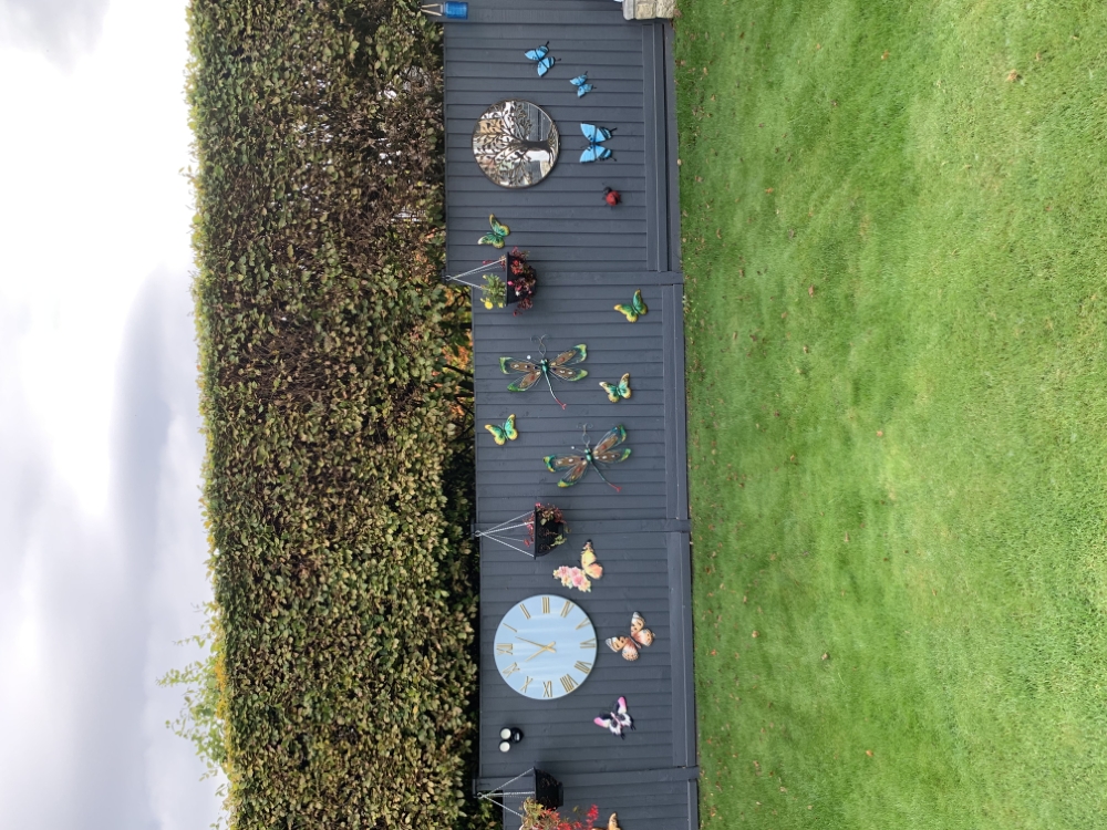 Neat lawn below a clipped hedge and decorated fence