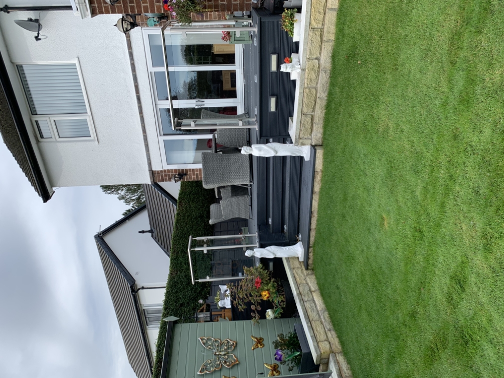 Maintained lawn in front of a raised deck and glass balustrade