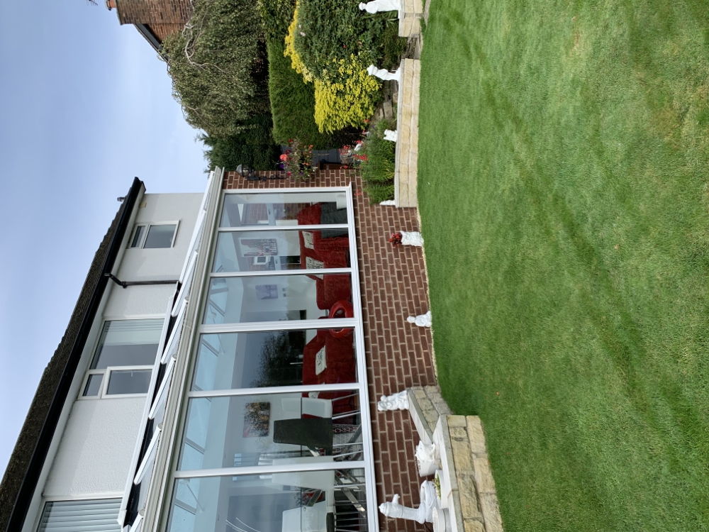 Maintained lawn and planted borders beside a conservatory